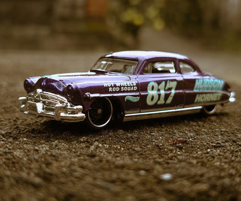 Lila Hot Wheels Modellauto mit der Nummer 817 auf rauem Untergrund.