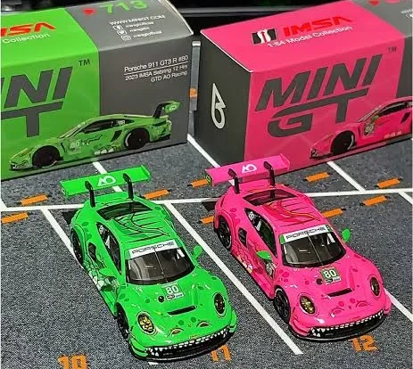 Zwei Porsche Modellautos in Grün und Pink, verpackt in Boxen mit "MINI GT"-Logo.