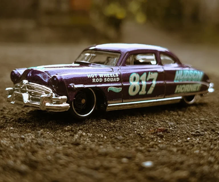 Lila Hot Wheels Modellauto mit der Nummer 817 auf rauem Untergrund.